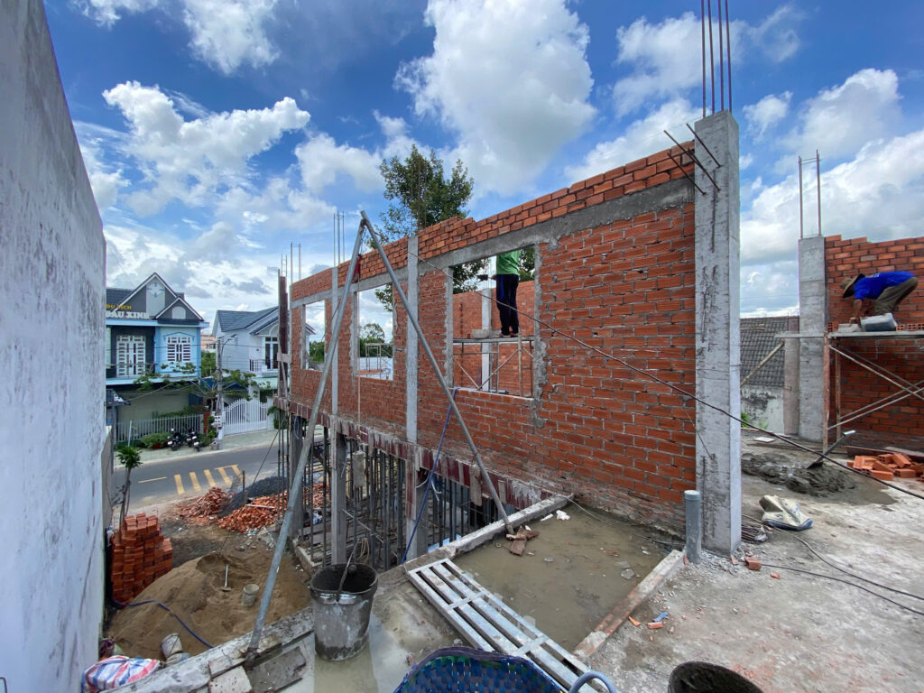 Nhà phố đang xây phần thô, tường gạch đỏ với các ô cửa chờ