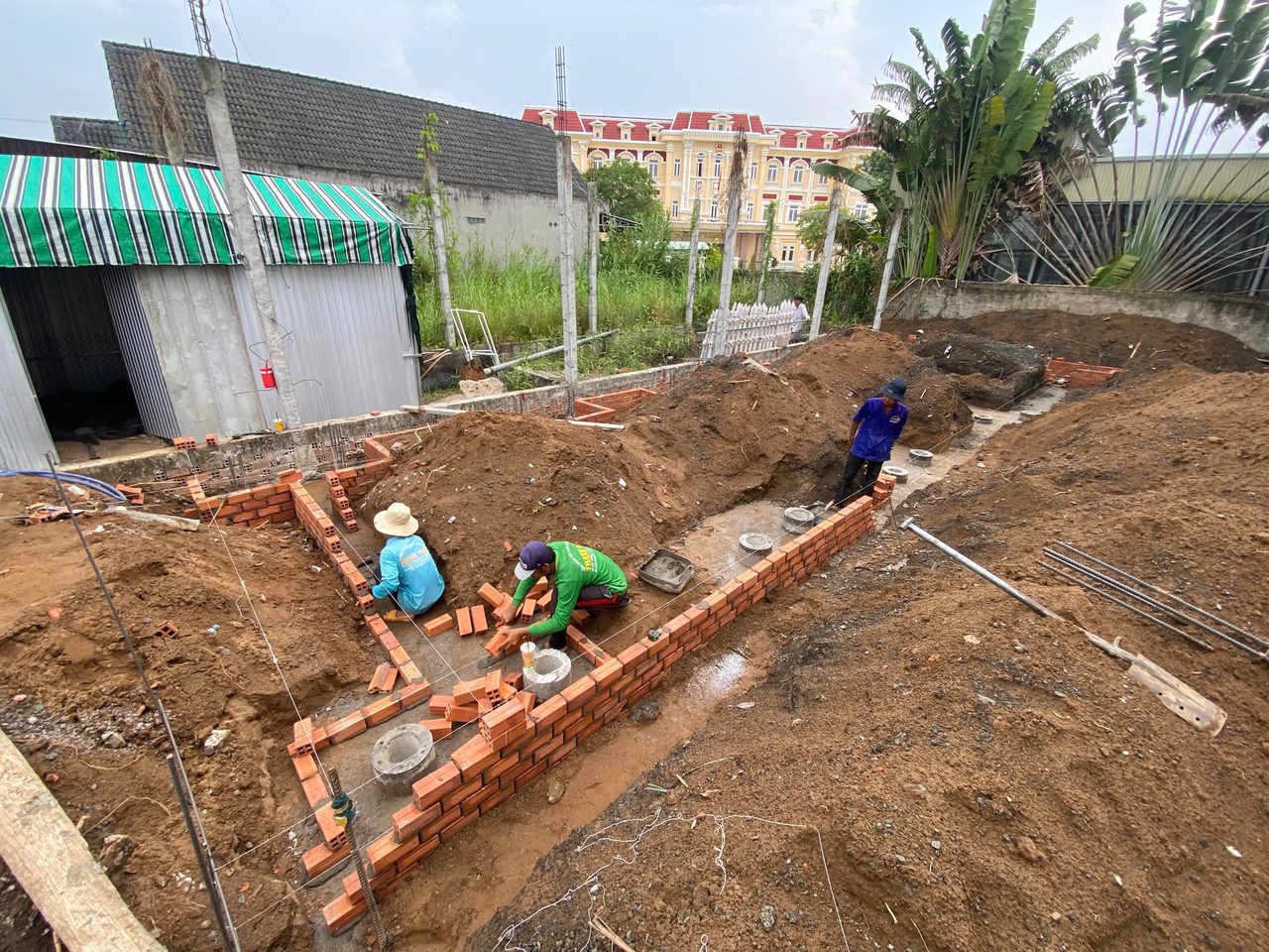Thợ xây tường móng bằng gạch đỏ, căng dây lấy cốt
