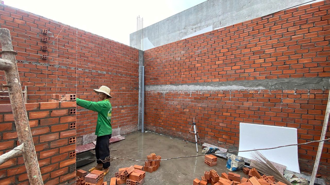 Thợ đặt gạch xây tường theo dây căng mực