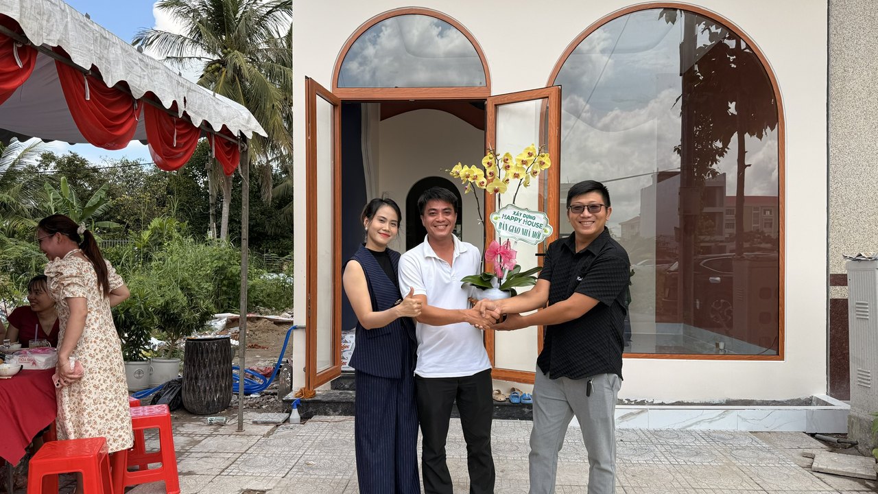 Ngô Đình Khuôn bắt tay bàn giao nhà mới cho hai vợ chồng chủ nhà, đứng trước cửa vòm căn nhà vừa hoàn thiện