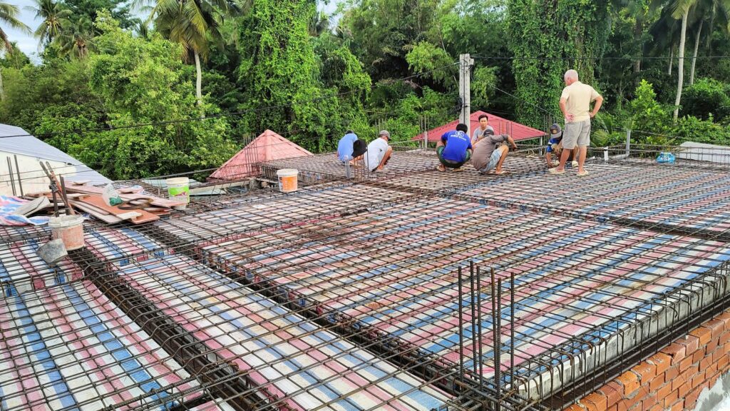 Sàn mái rộng đang đan thép, nhiều thợ ngồi buộc thép rải theo hàng