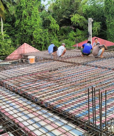 Sàn mái rộng đang đan thép, nhiều thợ ngồi buộc thép rải theo hàng